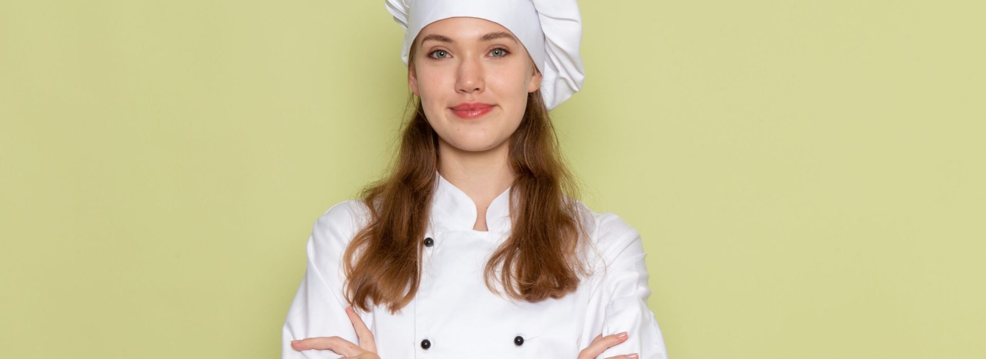 front view female cook in white cook suit smiling and posing on green background kitchen cuisine cooking food meal female